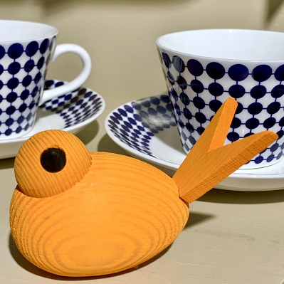 Träfågel i orange bets framför två Adamkoppar med blåvitt mönster av Stig Lindberg.
